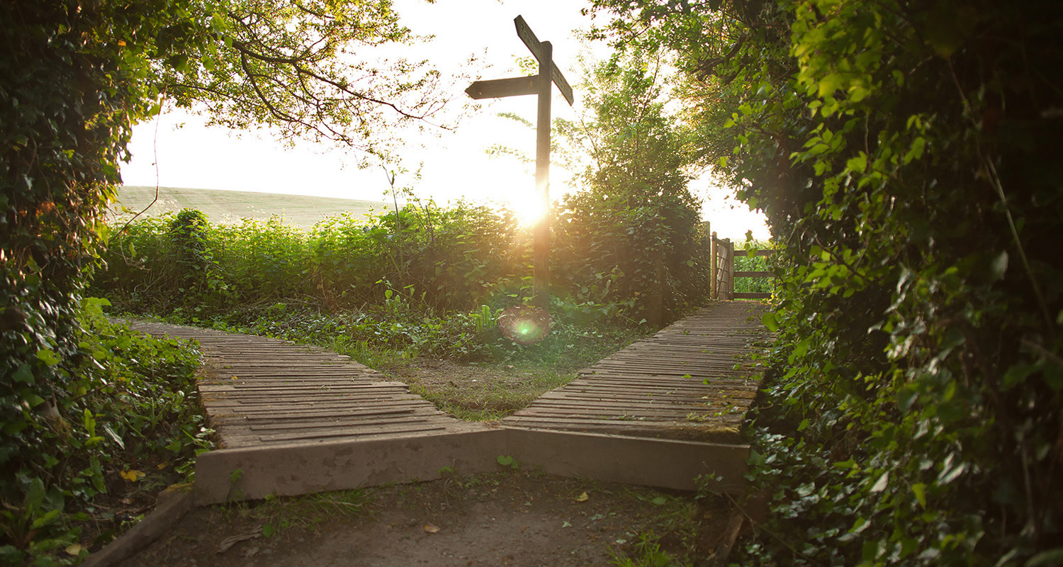 signpost on trail with sun low in sky